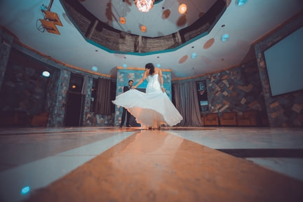 Picture of bride twirling her dress on dancefloor while groom watches 